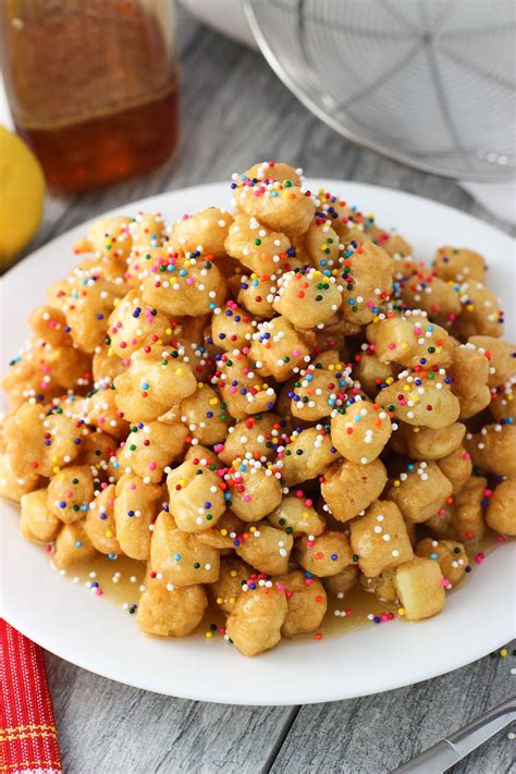 Struffoli are fried dough balls that are covered in honey and sprinkles, all served in a mound ...