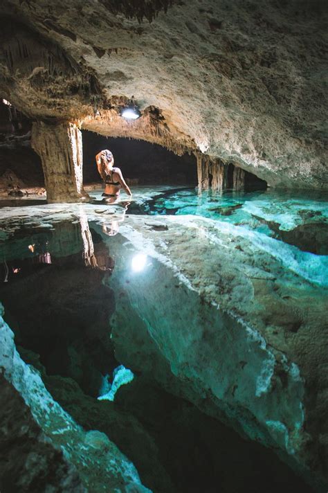 a man is standing in the water inside a cave