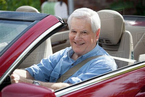 A cheerful senior man driving a convertible sports car - Stock Photo - Dissolve