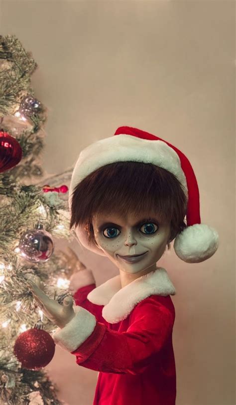 a close up of a doll near a christmas tree with ornaments on it's head