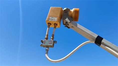 a camera attached to the side of a metal pole with a blue sky in the ...