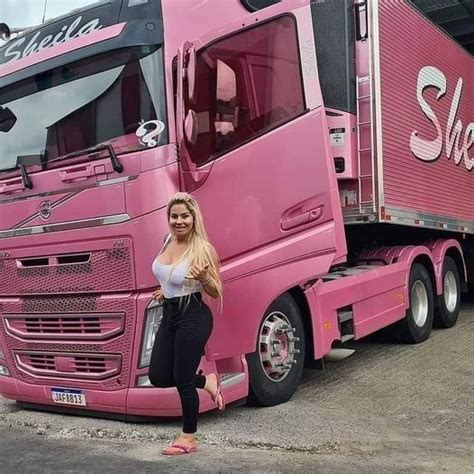 a woman standing in front of a pink semi - truck with the word she's on it