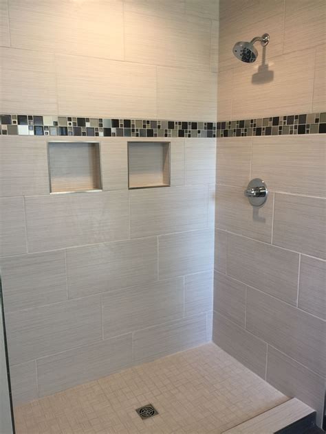 Custom tiled shower with 12x24 satiated tile run 1/3 staggered vertically with a glass and metal ...