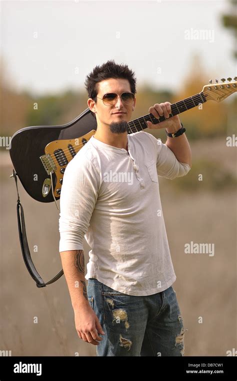 A rock musician wearing sunglasses carry brown electric guitar on left ...