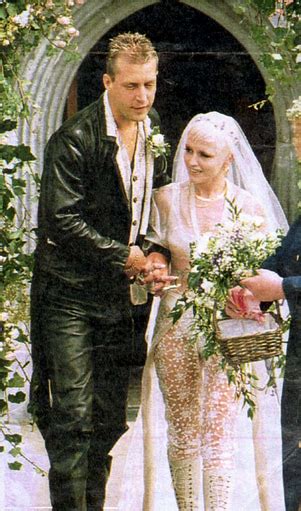 the bride and groom are walking down the aisle together in front of an archway with greenery