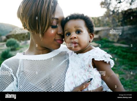 Black mother holding baby daughter in field Stock Photo - Alamy