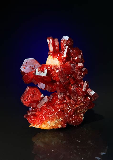 a cluster of red crystals sitting on top of a black table next to a blue background