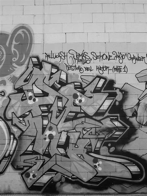 black and white photograph of graffiti on a brick wall