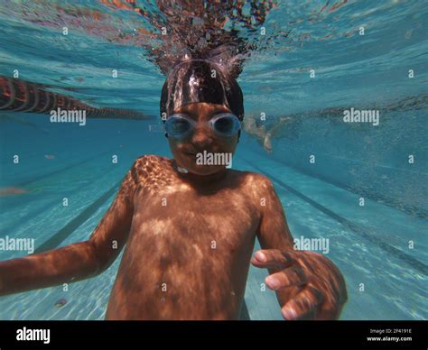 Boy underwater in goggles looking at camera, diving in swimming pool ...