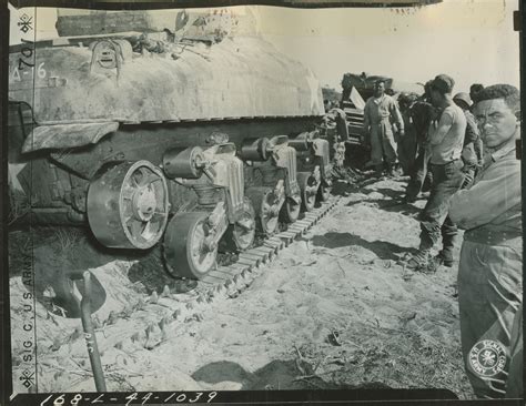 Tank crew members repairing a damaged M4 Sherman tank in the field ...