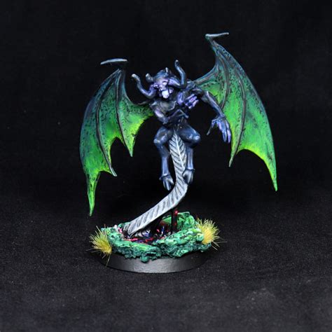a green and black dragon figurine sitting on top of a table