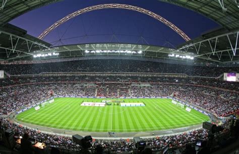 a stadium filled with lots of people sitting on top of a lush green ...