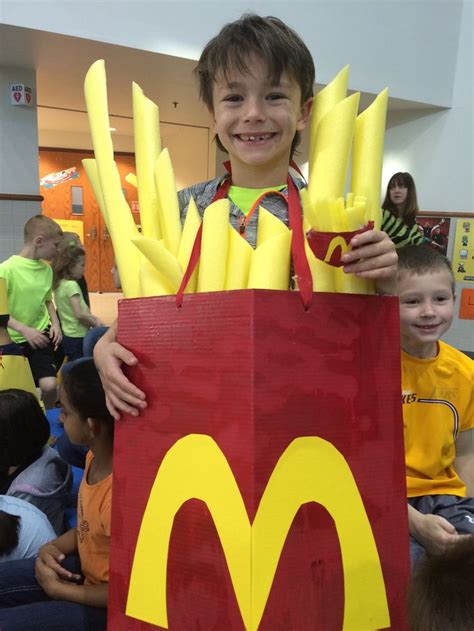 a young boy is dressed up as a mcdonald's bag with fries in it