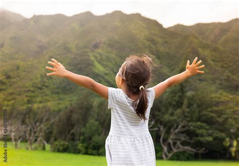 Happy people in nature. Little girl standing outside, arms raised ...