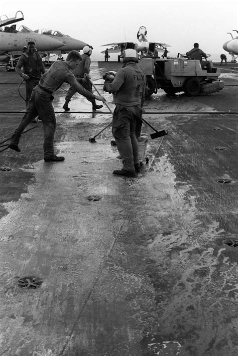 Crew members swab the flight deck of the aircraft carrier USS JOHN F ...