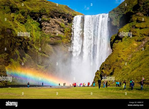 Iceland, Skogafoss waterfall with double rainbow and tourist admiring ...