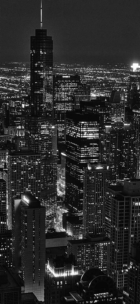 black and white cityscape at night with skyscrapers lit up in the distance