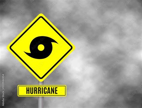 Hurricane sign road. Yellow hazard warning sign against grey sky - tornado warning, bad weather ...