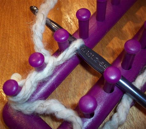 a pair of scissors and some yarn on a wooden table with purple pegs ...