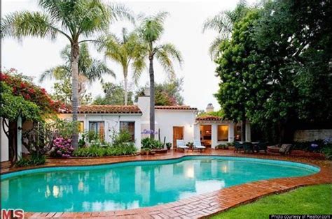 the pool is surrounded by palm trees and brick walkways that lead up to the house