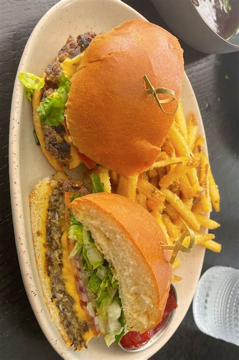 two cheeseburgers and fries on a white plate