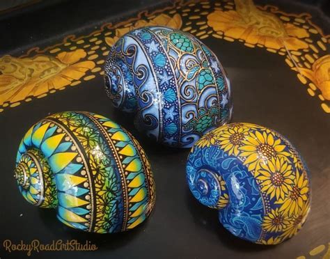 three painted eggs sitting on top of a black tray with yellow and blue designs around them