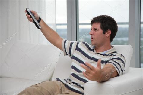 Angry TV Watcher on couch with remote control — Stock Photo © Mr.Interior #13944692