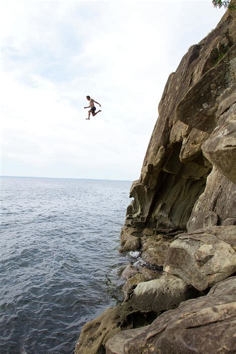 Man Jumping Off A Cliff Into Water Photograph by Adam Clark - Pixels