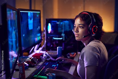 Teenage Girl Wearing Headset Gaming At Home Using Dual Computer Screens ...