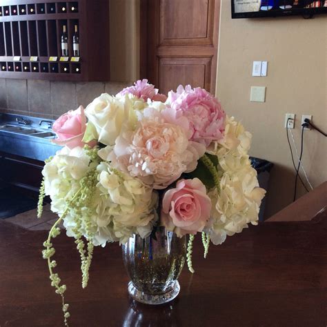 Centerpieces were in a antique glass gold vase with poeny, roses, hydrangeas, and hanging ...