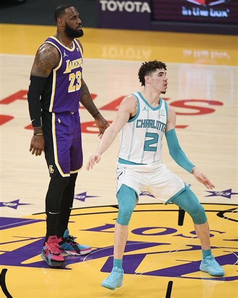 LaMelo Ball #2 of the Charlotte Hornets stands in front of LeBron James #23 of the Los Angeles ...