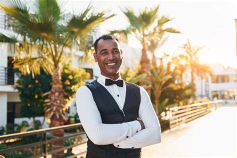 Posing for a camera. Black waiter in formal clothes is at his work ...