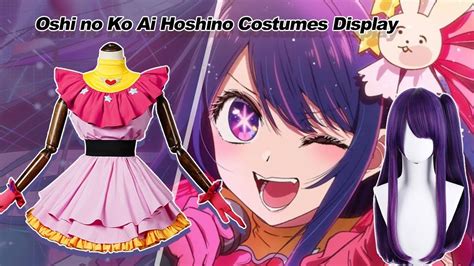 an anime cosplay with purple hair and pink eyes wearing a dress that ...