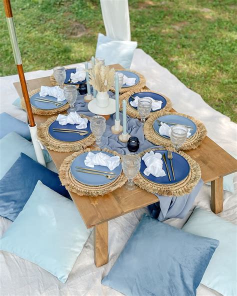 an outdoor table set with blue plates and napkins