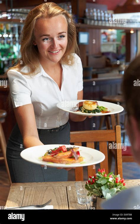 Waitress Serving Customer Sitting At Table In Restaurant Stock Photo - Alamy