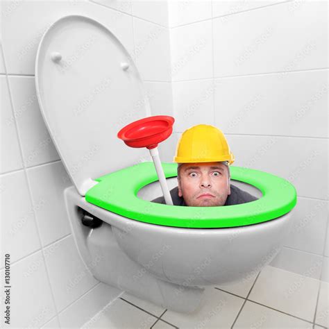 Funny repairman looking from toilet bowl with green seat in a modern ...