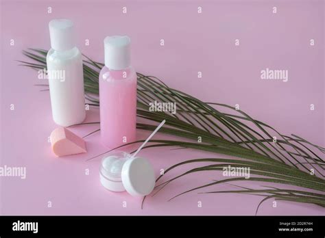 Cosmetic bottle containers with blank branding labels. Pink pastel background with green herbal ...