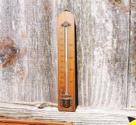 an old thermometer sitting on top of a wooden table next to a banana