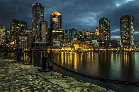 the city skyline is lit up at night with lights reflecting in the water and buildings