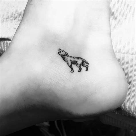 Tiny wolf tattoo located on the ankle.