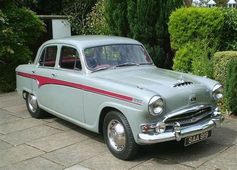 an old car is parked in front of some bushes