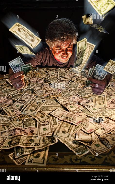 Greedy man playing with heap of money Stock Photo - Alamy