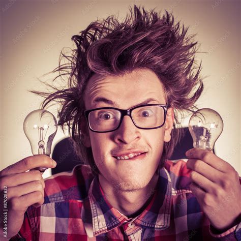 Smiling young nerd holding light bulbs Stock-Foto | Adobe Stock