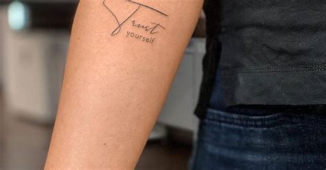 "Trust yourself" lettering tattoo on the inner forearm.