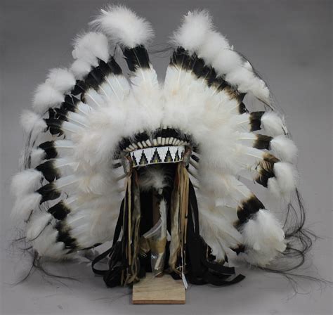 A late 20th century Native American feather headdress, mounted on a wooden display stand.