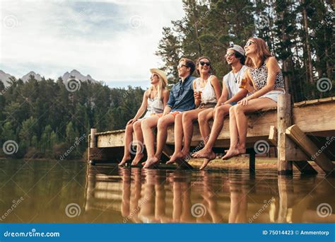 Group of Friends Sitting on Jetty at Lake Stock Image - Image of five ...