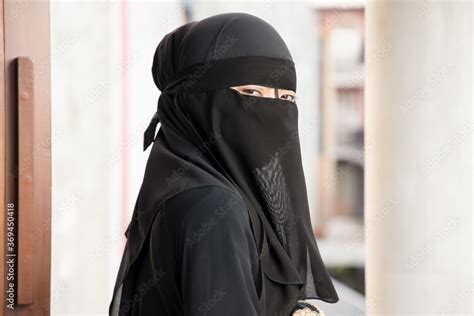 Portrait of Arabian woman looking at you while covering her face with ...