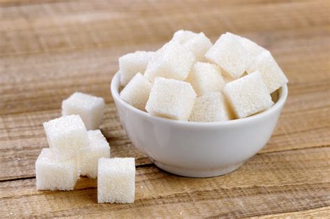 Sugar cubes in bowl on wooden table