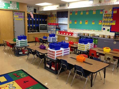 a classroom filled with lots of desks and colorful bins on top of them