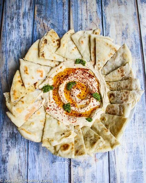 an assortment of pita breads with sauce and herbs on a blue wooden table